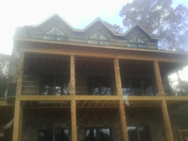 Dormers and porch framing on a large log home under construction — Roof Coating work by our crew in Conway