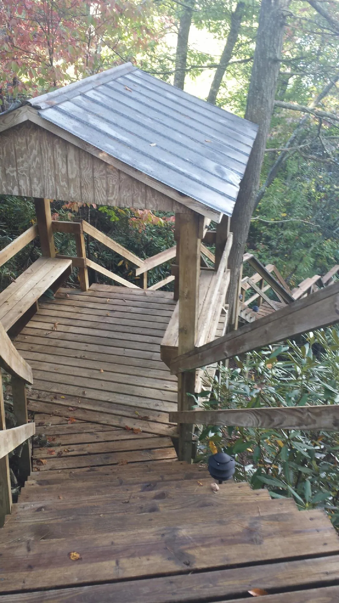 Metal roofed shelter over wooden steps on a wooded walkway — Skylight Repair & Installation work by our crew in Conway
