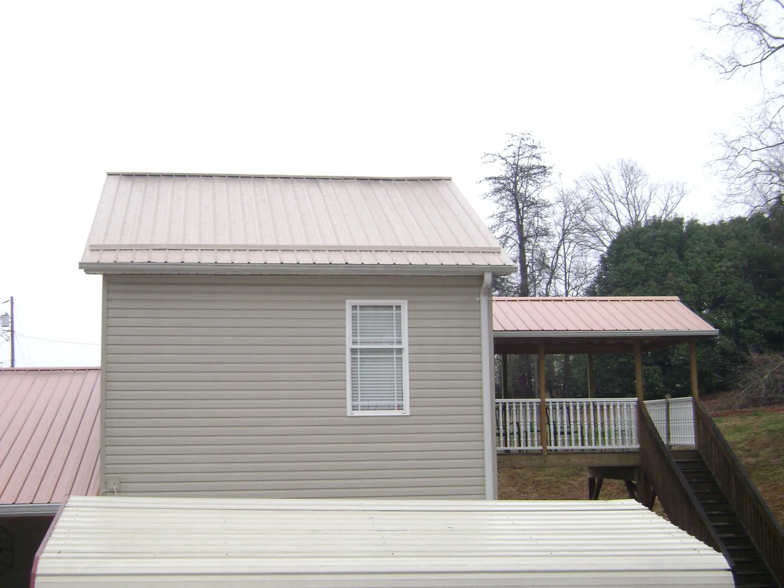 Tan metal roofs on a two story addition and attached porch, from a Roof Replacement job in Conway